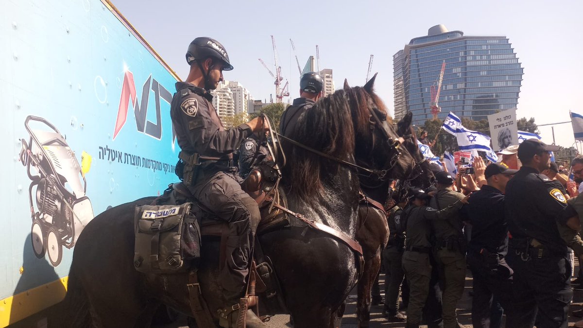 Policemen on horses push protesters in a major road in Tel Aviv