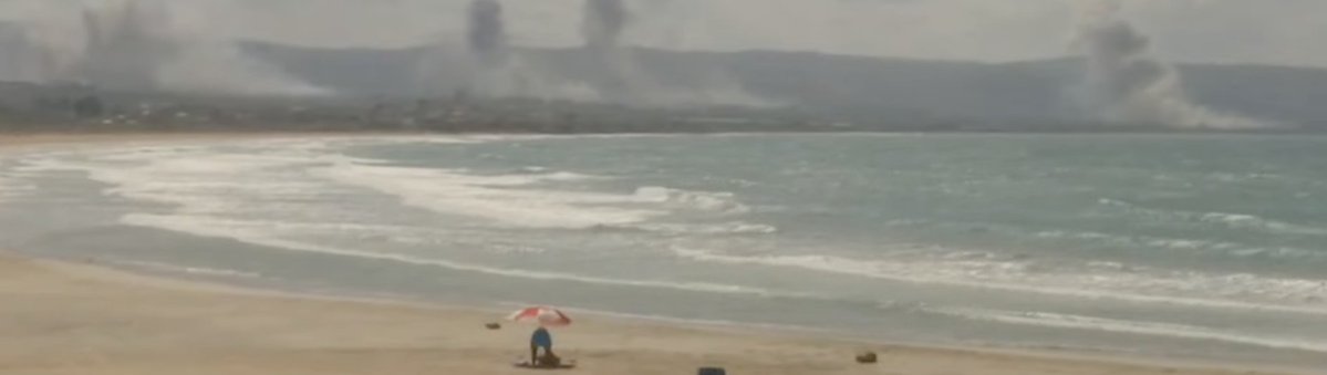 Person seen on the beach in Lebanon as the background is filled with Israeli airstrikes