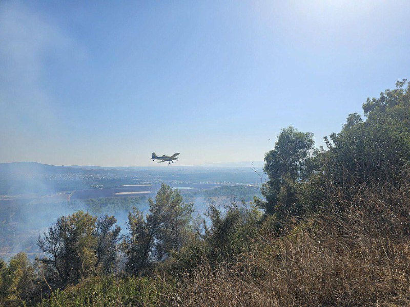 Serviços de emergência israelenses usam aeronaves para extinguir um incêndio que começou no assentamento de Shlomi depois que um míssil do Hezbollah o atingiu.