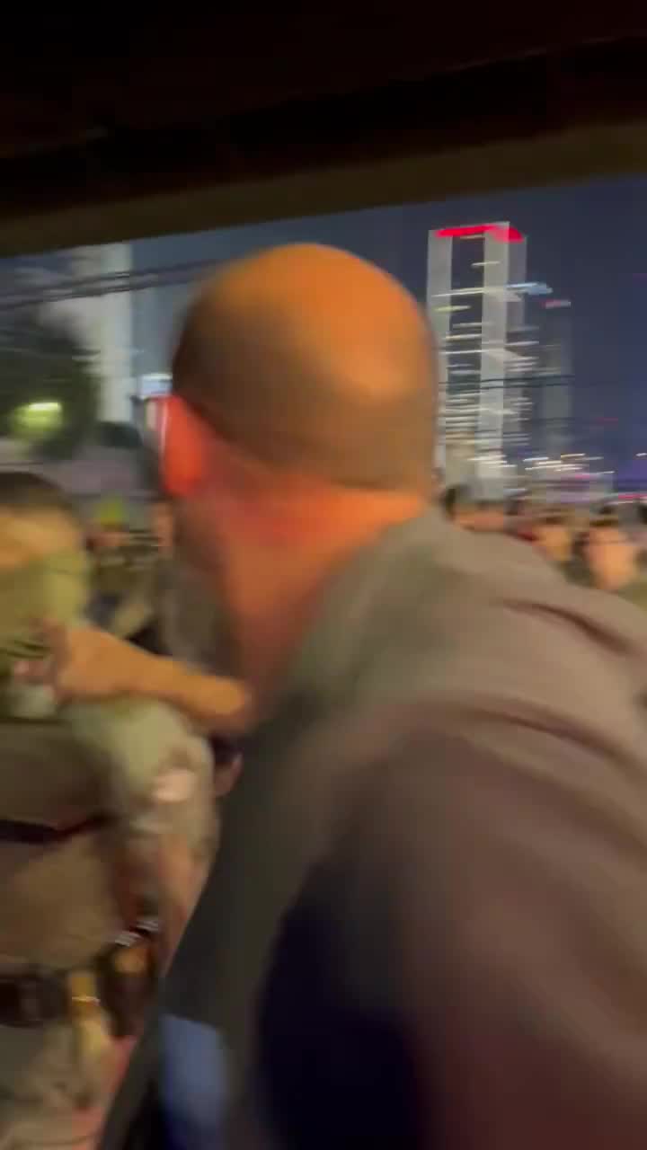 Police officers in Ayalon South move in a large group to put out fires with fire extinguishers, hundreds of protesters behind them