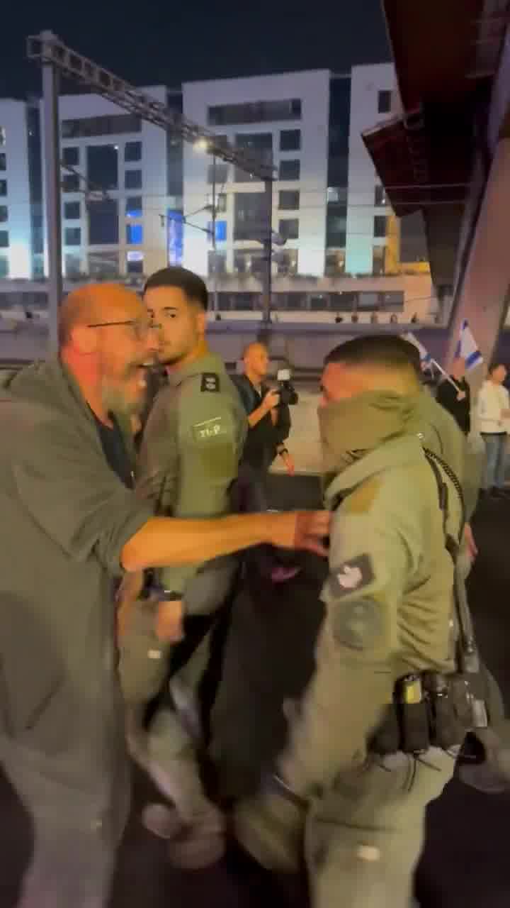 Police officers in Ayalon South move in a large group to put out fires with fire extinguishers, hundreds of protesters behind them